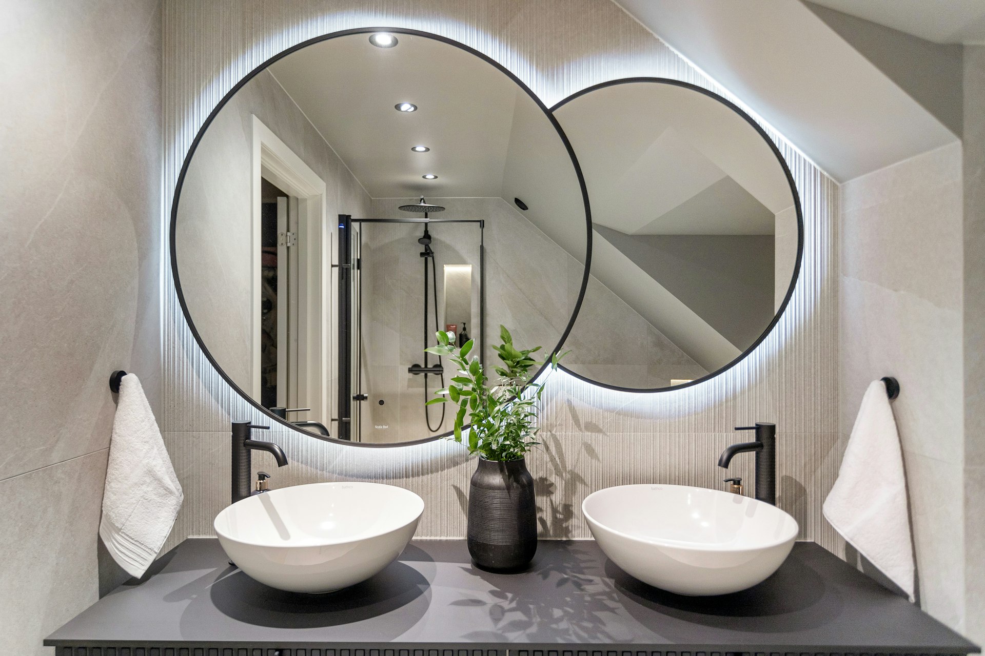 A bathroom with two sinks and a round mirror